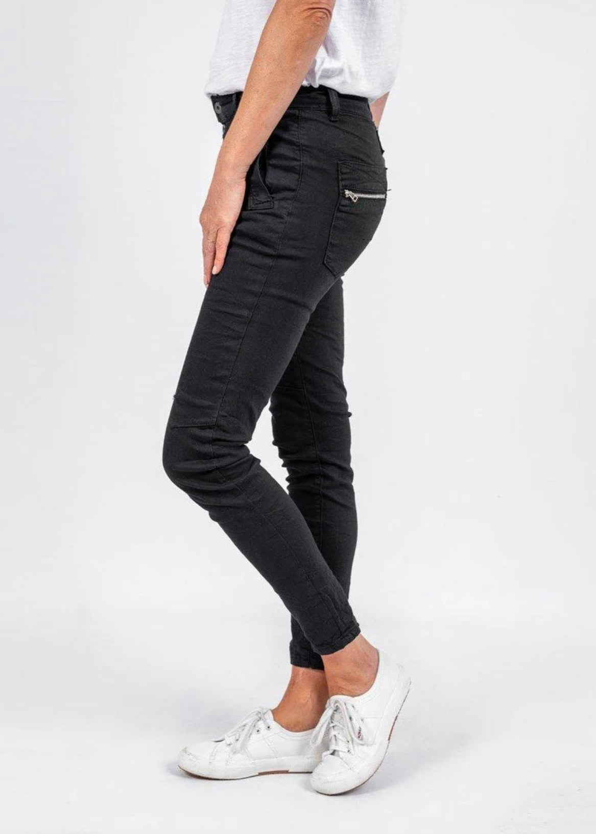 Person wearing black pants and white shoes on a white background