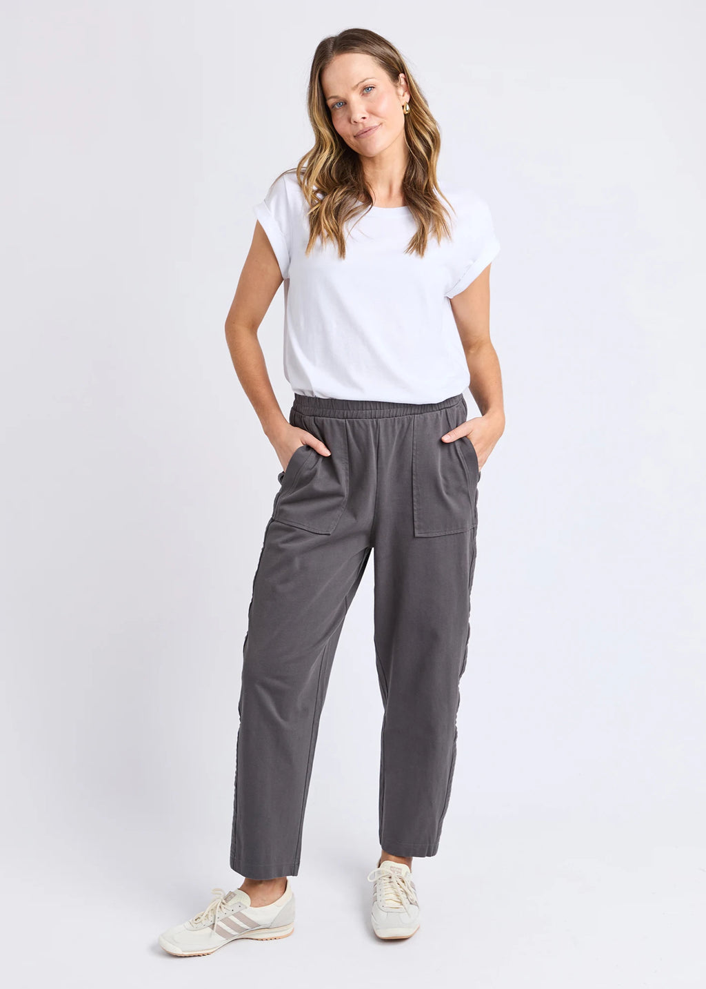 Woman wearing a white t-shirt and gray pants on a white background